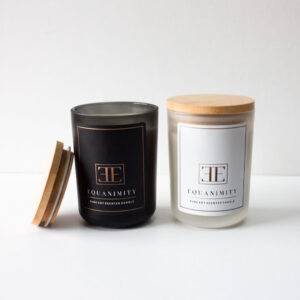 Two soy scented candles with wooden lids and the label “Equanimity” are pictured on a table.